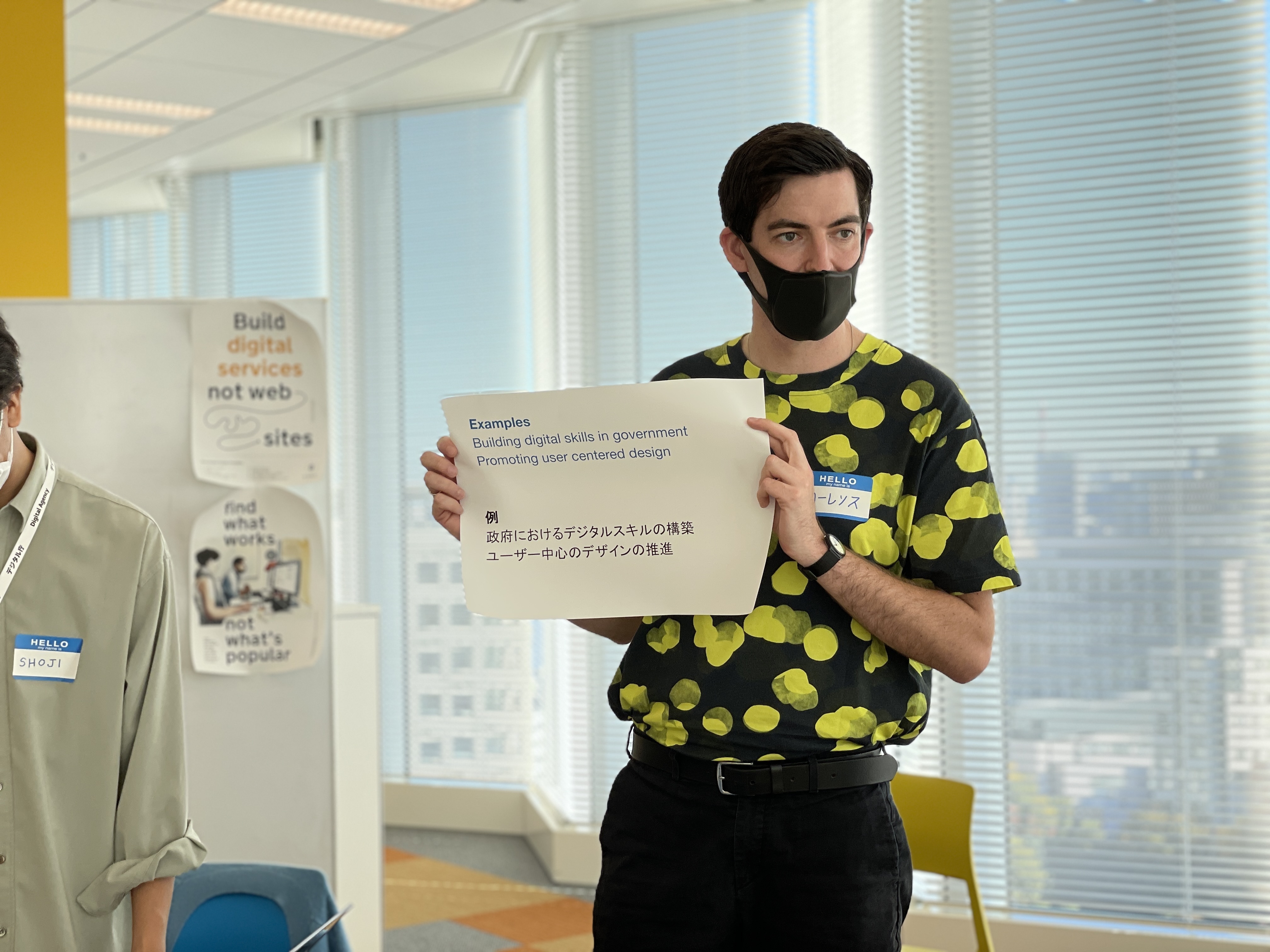 Laurence holding up a piece of paper that says building digital skills in government, promoting user centred design